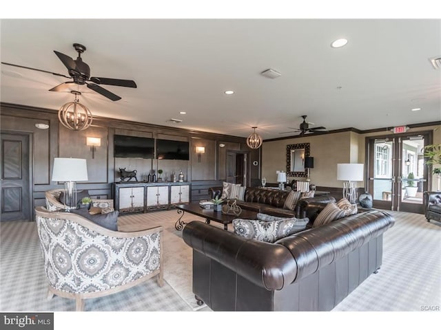 living room with light carpet, ceiling fan with notable chandelier, and ornamental molding