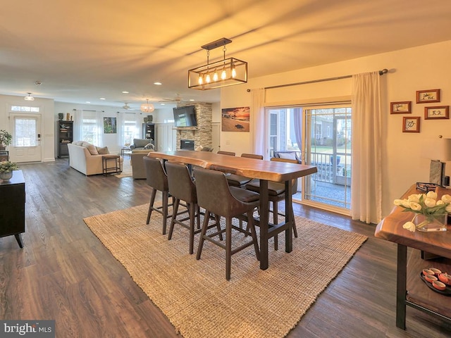 dining area featuring a fireplace, plenty of natural light, dark wood-type flooring, and ceiling fan