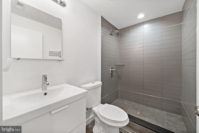 bathroom featuring tiled shower, vanity, and toilet