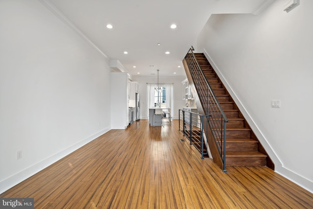 interior space with a chandelier, wood-type flooring, and crown molding