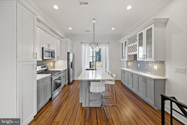 kitchen with gray cabinetry, dark wood-type flooring, stainless steel appliances, and ornamental molding