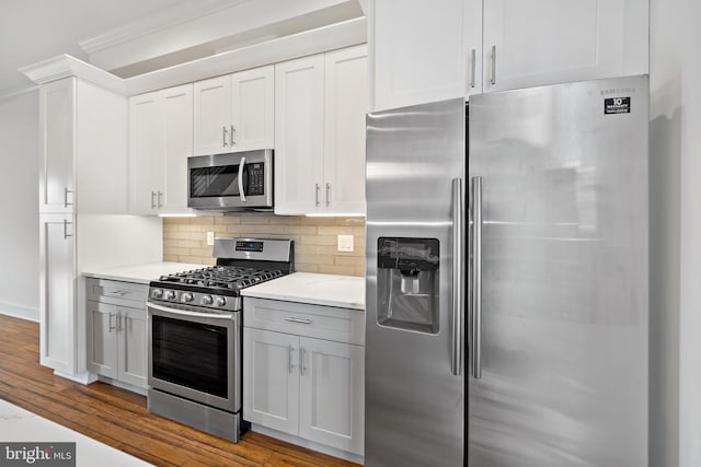 kitchen featuring white cabinetry, light stone countertops, backsplash, light hardwood / wood-style floors, and appliances with stainless steel finishes