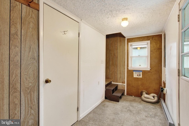 bathroom featuring a textured ceiling, wooden walls, crown molding, and a baseboard heating unit