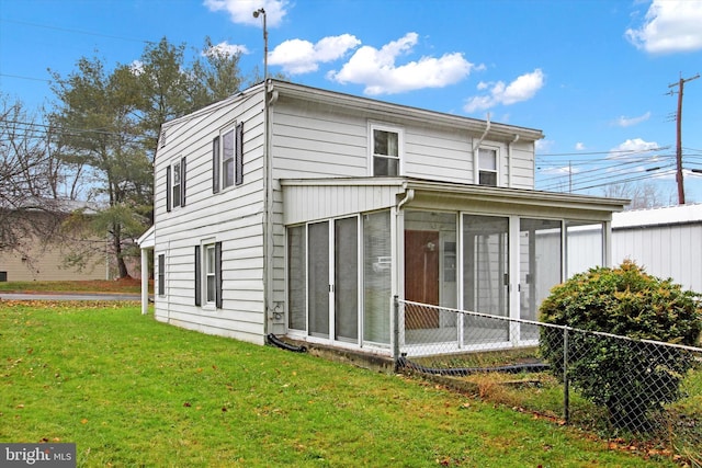 rear view of house featuring a sunroom and a lawn