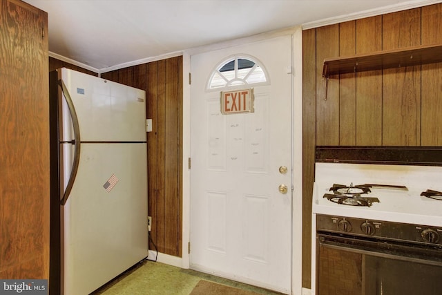 kitchen featuring wood walls, ornamental molding, and white refrigerator