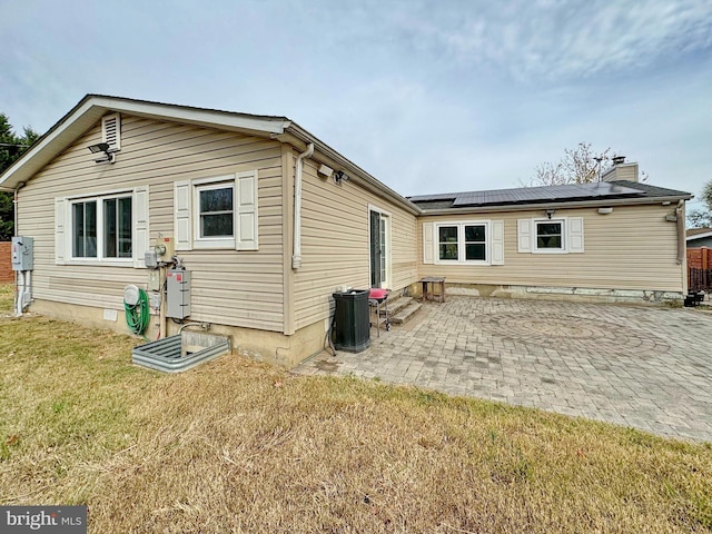 back of house with a lawn, solar panels, and a patio area