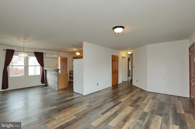 unfurnished living room with ceiling fan with notable chandelier, dark hardwood / wood-style flooring, and a wall unit AC