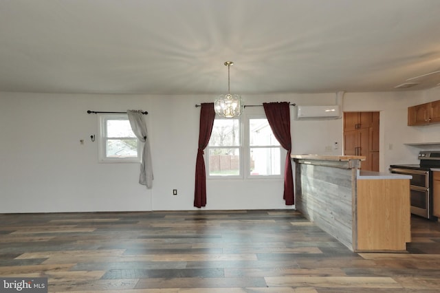 kitchen featuring stainless steel electric range, dark hardwood / wood-style flooring, an AC wall unit, and an inviting chandelier