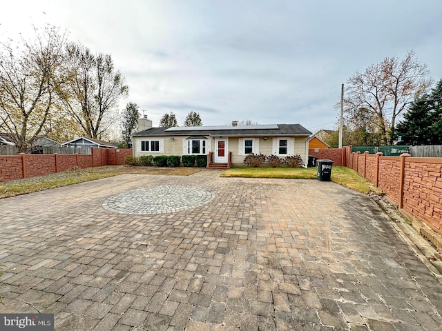 single story home with solar panels and a patio