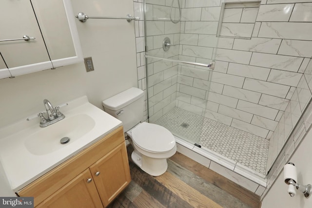 bathroom featuring vanity, toilet, a shower with shower door, and wood-type flooring