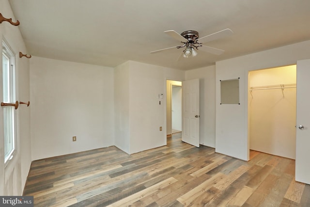 unfurnished bedroom with ceiling fan, light hardwood / wood-style floors, a walk in closet, and a closet