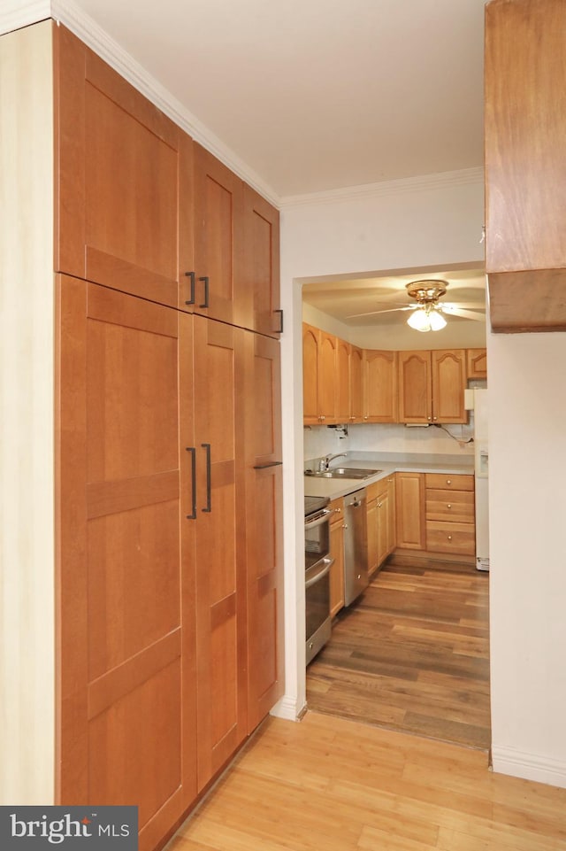 kitchen featuring sink, ornamental molding, stainless steel appliances, and light wood-type flooring