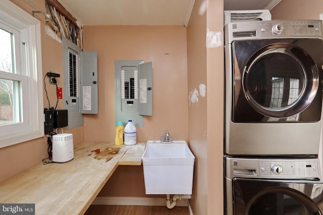 washroom with hardwood / wood-style flooring, stacked washer and dryer, sink, and electric panel