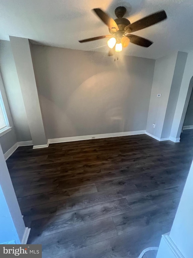 empty room with ceiling fan, dark wood-type flooring, and a textured ceiling