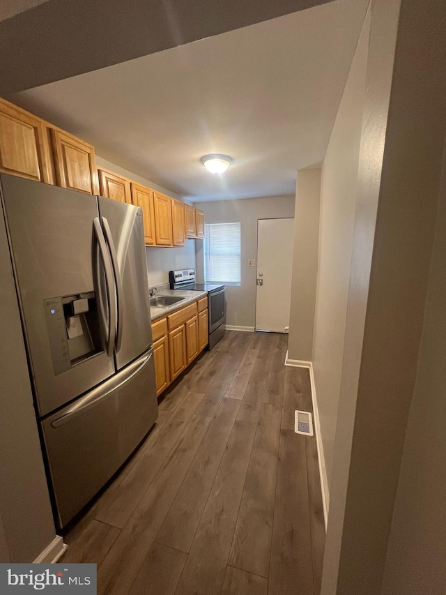 kitchen with light brown cabinetry, sink, dark wood-type flooring, and appliances with stainless steel finishes