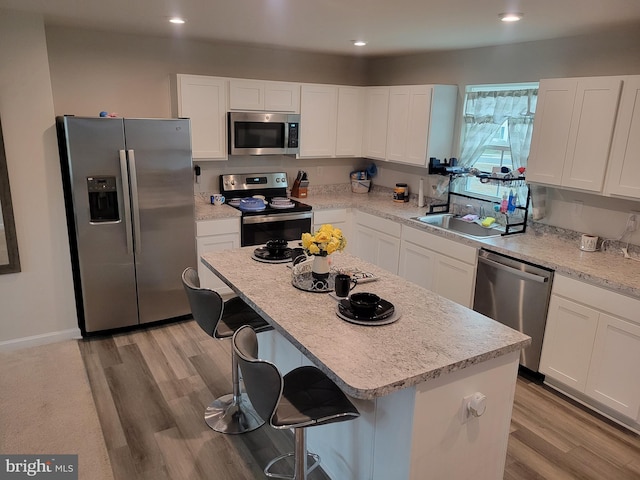 kitchen featuring white cabinets, a center island, light wood-type flooring, and stainless steel appliances