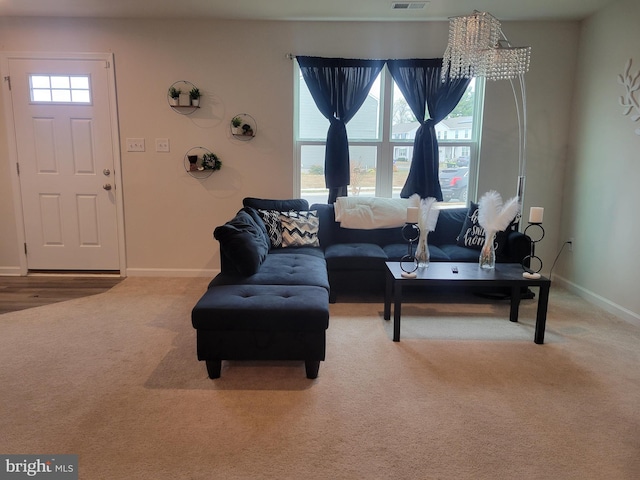 living room featuring a chandelier, carpet, and a healthy amount of sunlight