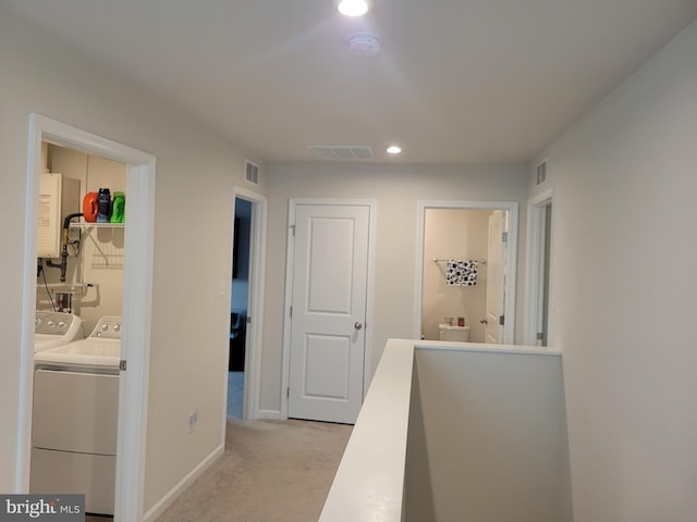 corridor featuring light carpet and washer and clothes dryer