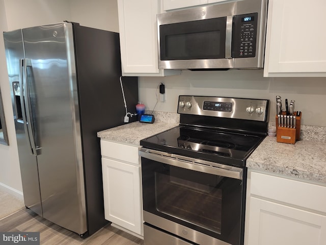 kitchen featuring white cabinets, stainless steel appliances, light hardwood / wood-style flooring, and light stone countertops