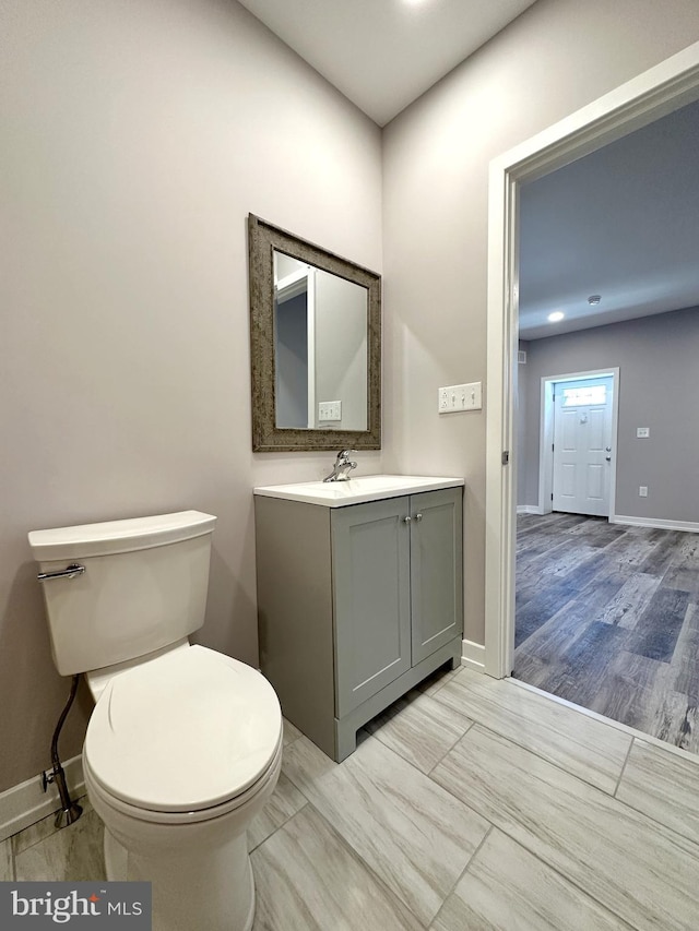 bathroom featuring wood-type flooring, vanity, and toilet