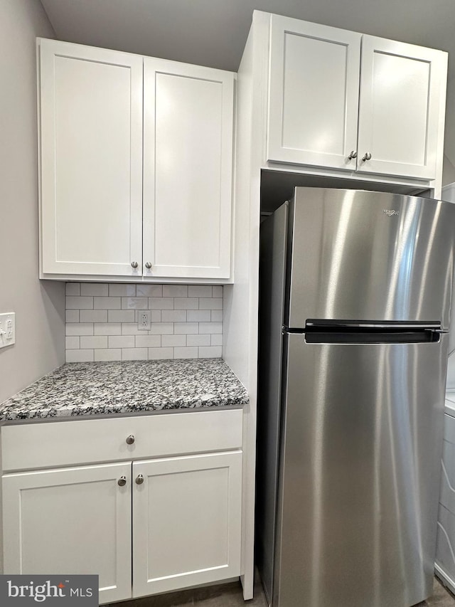 kitchen featuring white cabinets and stainless steel refrigerator