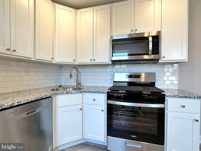 kitchen with white cabinets, light stone counters, sink, and appliances with stainless steel finishes