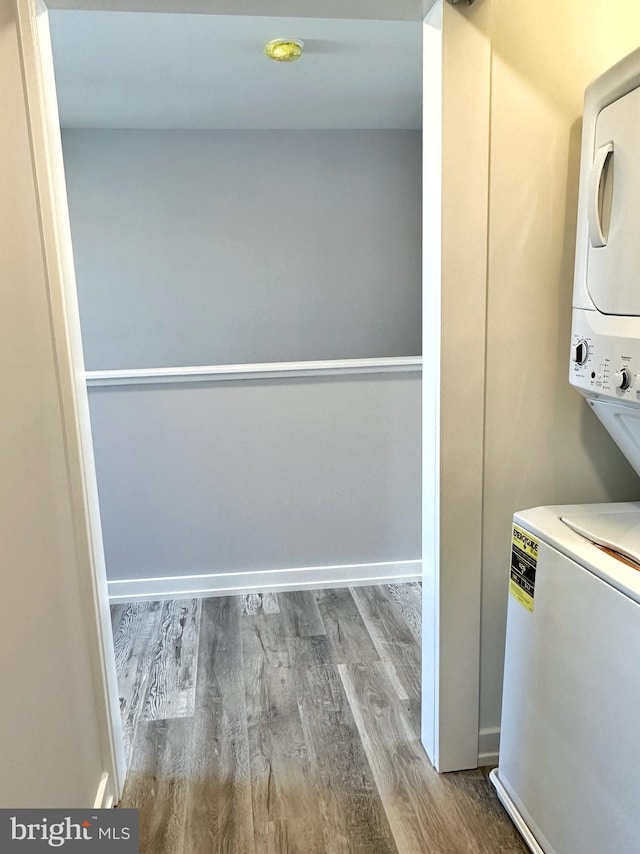 laundry area featuring hardwood / wood-style floors and stacked washer and clothes dryer