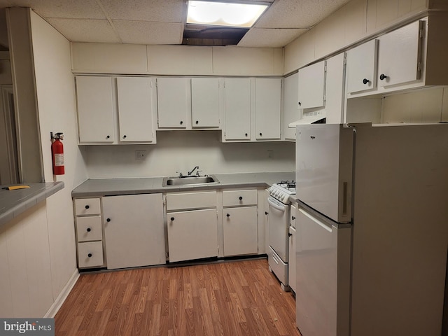 kitchen featuring a drop ceiling, light hardwood / wood-style floors, sink, white appliances, and white cabinetry