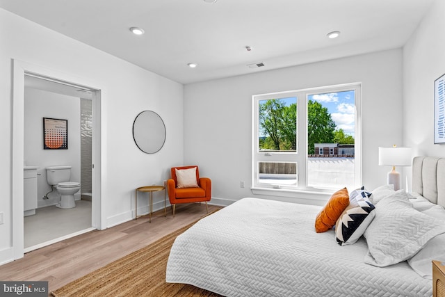 bedroom with ensuite bathroom and light wood-type flooring