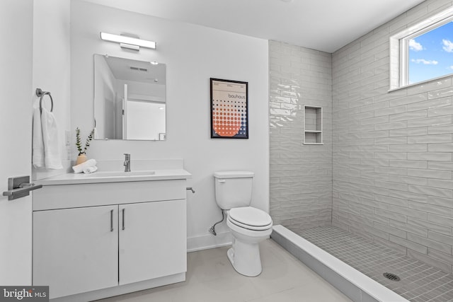 bathroom with tiled shower, vanity, toilet, and tile patterned floors