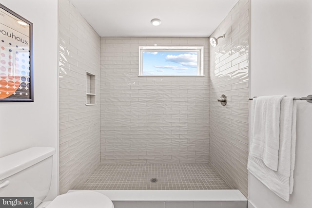 bathroom featuring toilet and a tile shower