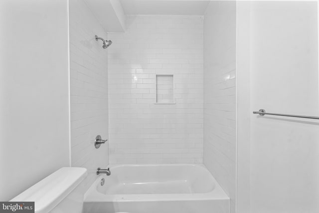 bathroom with tiled shower / bath combo and toilet