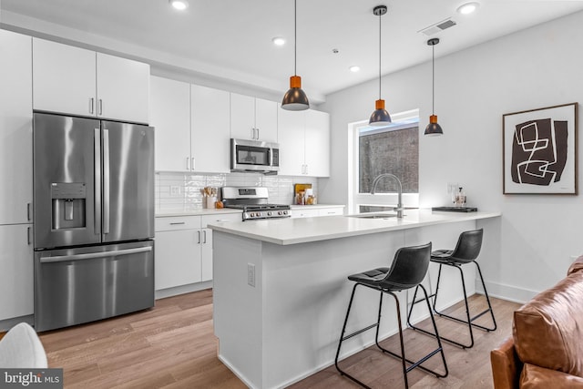 kitchen featuring sink, white cabinetry, decorative light fixtures, stainless steel appliances, and backsplash