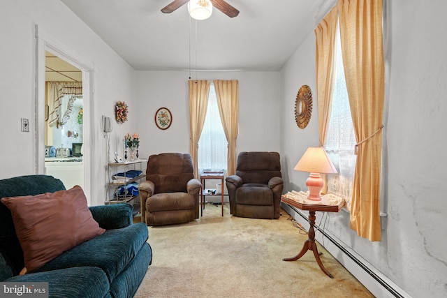 living area with carpet flooring, ceiling fan, and a baseboard heating unit