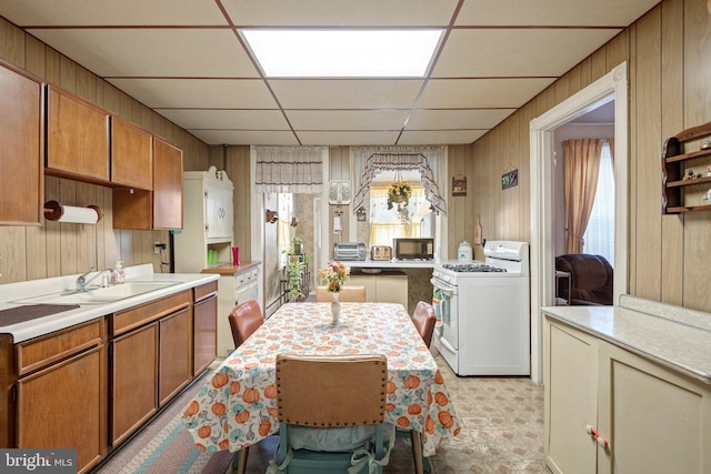 kitchen featuring a paneled ceiling, white range with gas cooktop, and wood walls