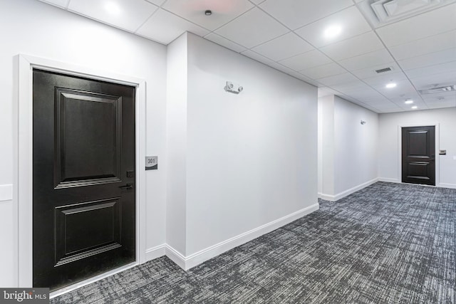 interior space with a paneled ceiling and dark colored carpet