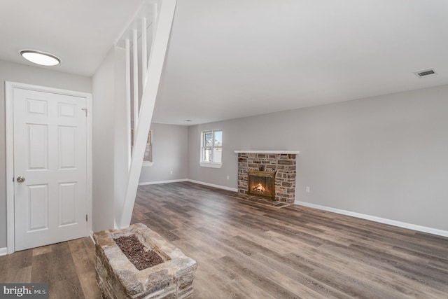 unfurnished living room featuring hardwood / wood-style floors and a stone fireplace