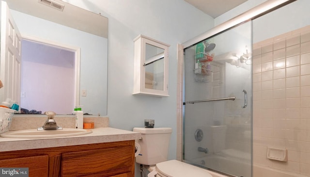 full bathroom featuring shower / bath combination with glass door, vanity, and toilet