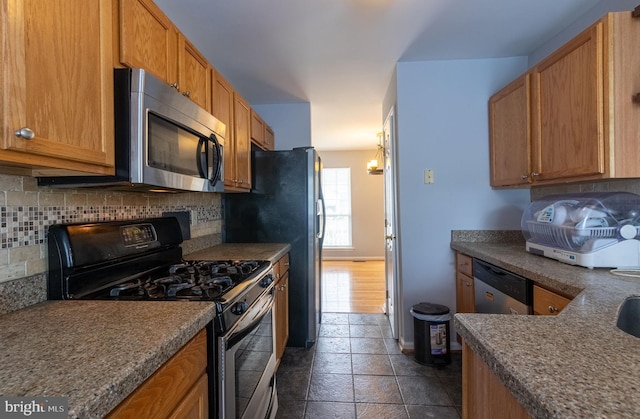 kitchen with black appliances, dark tile patterned flooring, and tasteful backsplash