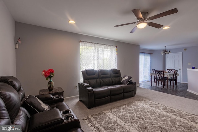 carpeted living room featuring ceiling fan with notable chandelier