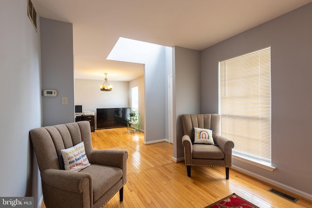 sitting room with wood-type flooring and a notable chandelier