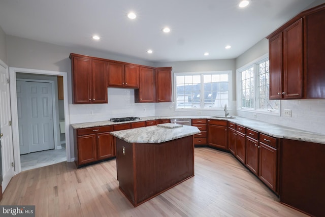 kitchen featuring gas stovetop, a center island, light hardwood / wood-style floors, and sink