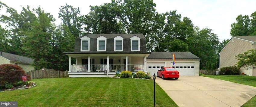 view of front facade featuring a garage, covered porch, and a front yard