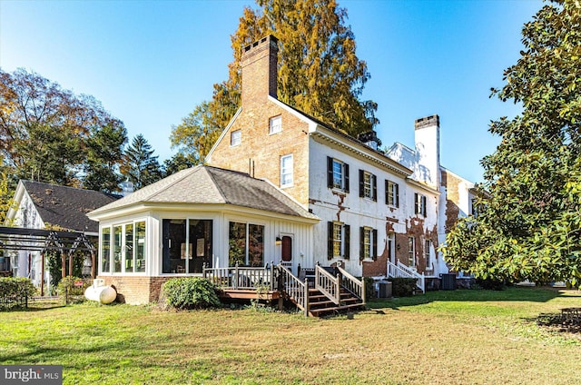 rear view of house with a sunroom, central air condition unit, a yard, and a wooden deck