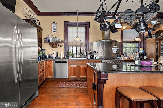 kitchen featuring pendant lighting, dark wood-type flooring, crown molding, a kitchen bar, and stainless steel appliances