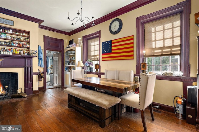 dining room featuring built in features, dark hardwood / wood-style flooring, an inviting chandelier, and crown molding