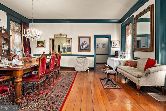 dining room with a chandelier, wood-type flooring, and ornamental molding