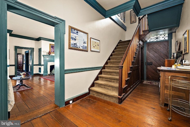 stairs with crown molding and wood-type flooring