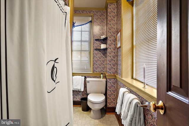 bathroom featuring ornamental molding, toilet, and a healthy amount of sunlight