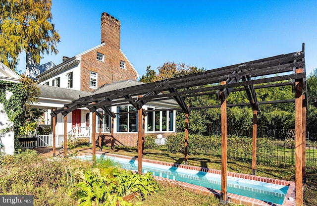 rear view of property featuring a fenced in pool and a pergola